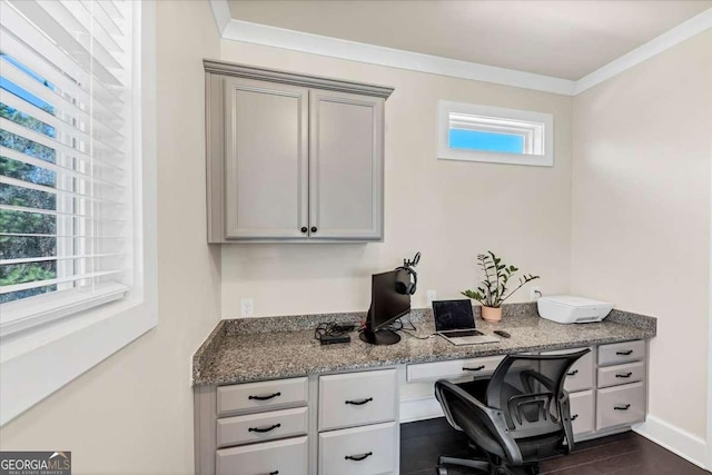 home office with dark wood-type flooring, built in desk, and ornamental molding