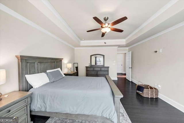 bedroom featuring ceiling fan, ornamental molding, dark wood-type flooring, and a tray ceiling