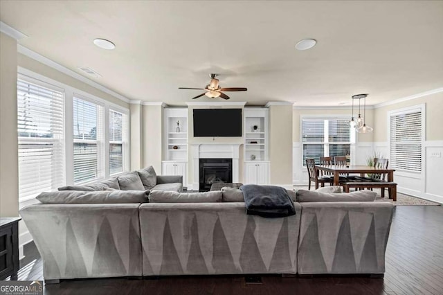 living room with ceiling fan, dark wood-type flooring, and ornamental molding