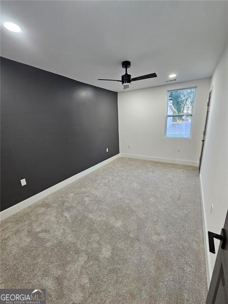 empty room featuring light colored carpet and ceiling fan