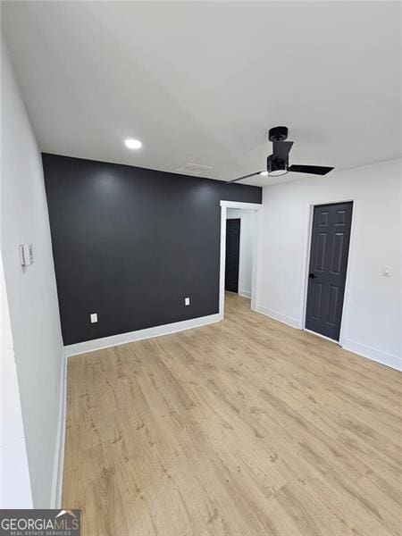 empty room with ceiling fan and light hardwood / wood-style flooring