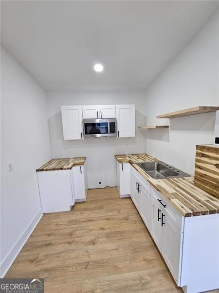 kitchen featuring white cabinetry, black electric stovetop, wooden counters, and light wood-type flooring