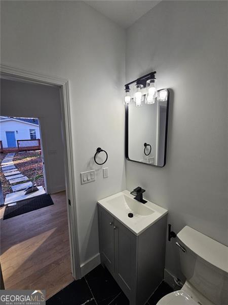 bathroom with hardwood / wood-style floors, vanity, and toilet