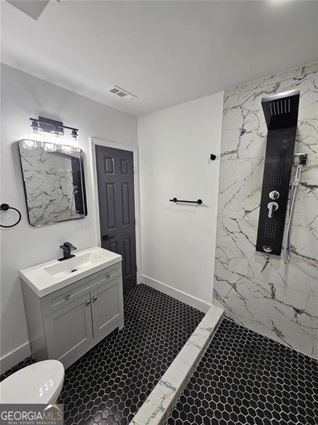 bathroom with toilet, vanity, tile walls, and walk in shower