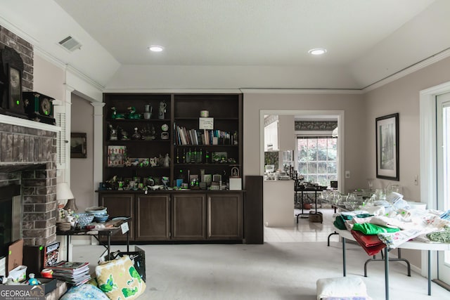 bar with a brick fireplace, crown molding, lofted ceiling, light carpet, and dark brown cabinets