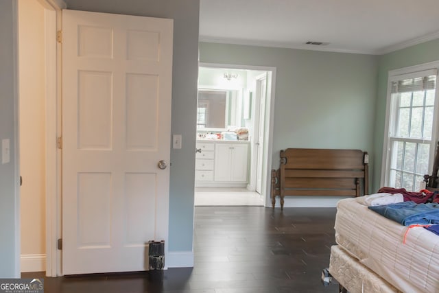 bedroom featuring ornamental molding, dark wood-type flooring, and ensuite bath