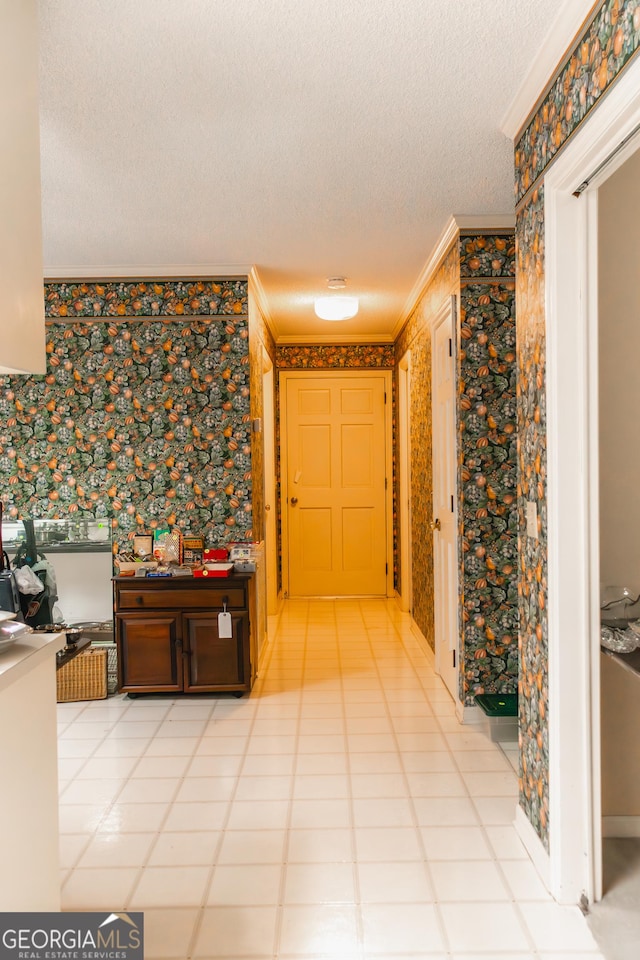 hall featuring a textured ceiling, light tile patterned floors, and crown molding