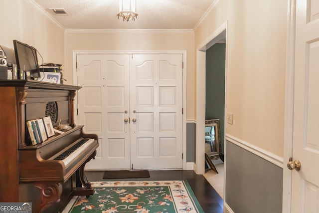 foyer with crown molding and a textured ceiling