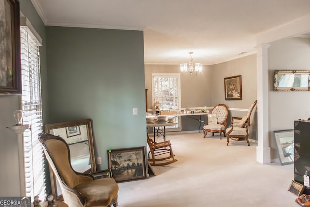 sitting room with an inviting chandelier, carpet floors, crown molding, and ornate columns