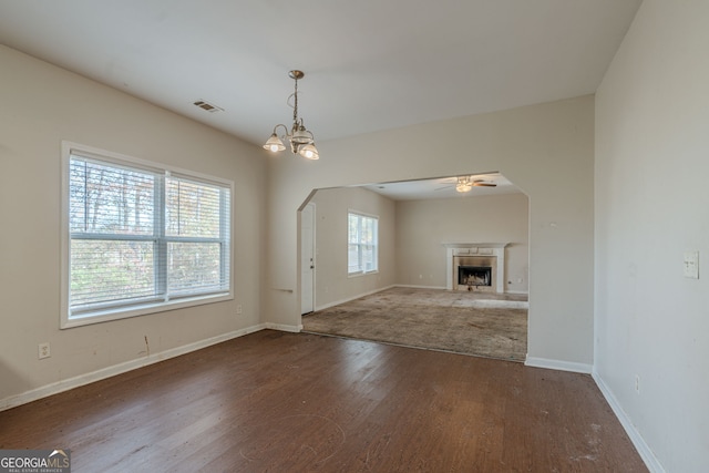 unfurnished living room featuring hardwood / wood-style floors and ceiling fan with notable chandelier