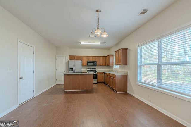 kitchen featuring pendant lighting, a center island, appliances with stainless steel finishes, a notable chandelier, and wood-type flooring