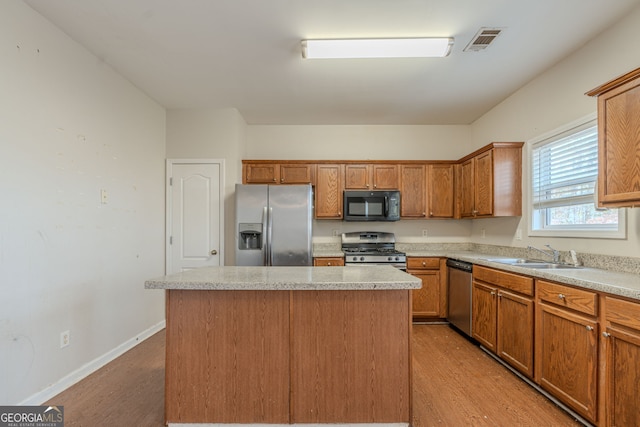 kitchen with a center island, stainless steel appliances, light hardwood / wood-style flooring, and sink