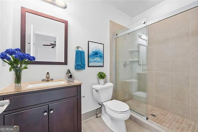 bathroom with vanity, a shower with door, ceiling fan, tile patterned flooring, and toilet