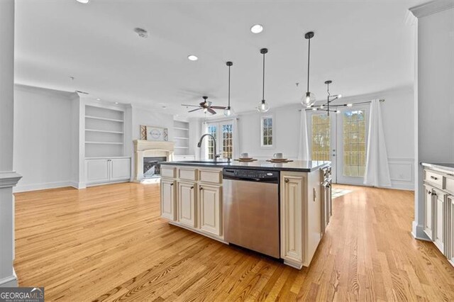 kitchen with dishwasher, a center island with sink, sink, light wood-type flooring, and decorative light fixtures