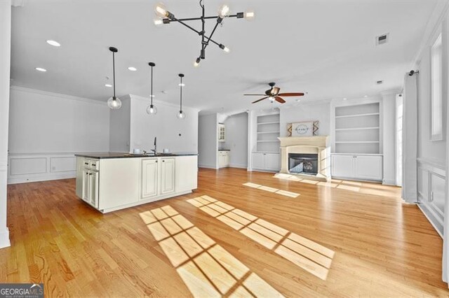 kitchen with pendant lighting, white cabinets, built in features, and light hardwood / wood-style flooring