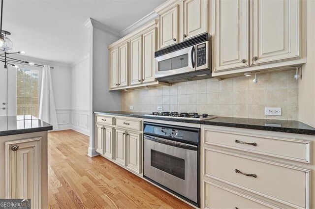 kitchen with stainless steel appliances, light hardwood / wood-style flooring, backsplash, crown molding, and cream cabinets