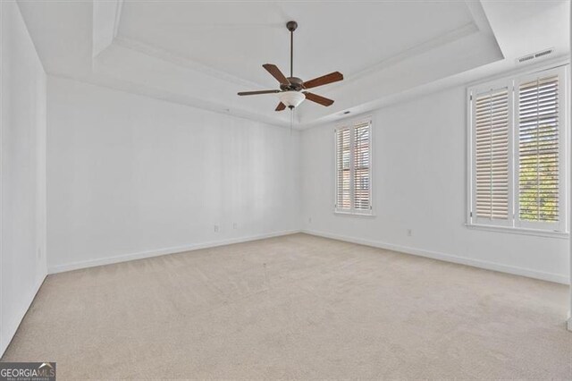 carpeted empty room with ceiling fan and a raised ceiling