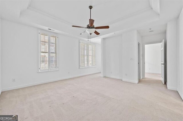 carpeted spare room featuring a raised ceiling and ceiling fan