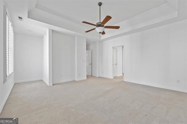 unfurnished bedroom featuring a raised ceiling, ceiling fan, and light carpet