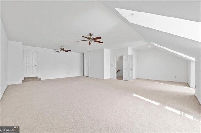 bonus room featuring light colored carpet, lofted ceiling with skylight, and ceiling fan