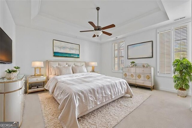 carpeted bedroom featuring a raised ceiling and ceiling fan