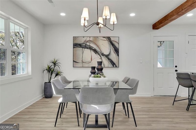 dining space featuring beamed ceiling, light wood-type flooring, and an inviting chandelier