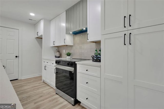 kitchen with white cabinetry, stainless steel electric range oven, light hardwood / wood-style flooring, range hood, and backsplash