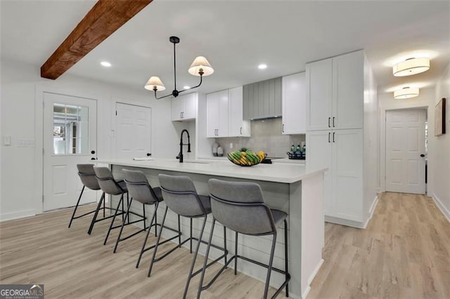 kitchen with a breakfast bar, a spacious island, light wood-type flooring, decorative light fixtures, and beam ceiling