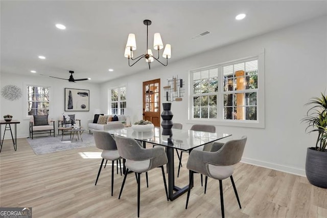 dining space with ceiling fan with notable chandelier, light hardwood / wood-style floors, and plenty of natural light