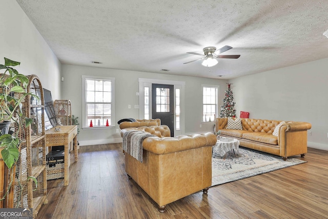 living room featuring a textured ceiling, ceiling fan, and dark hardwood / wood-style floors