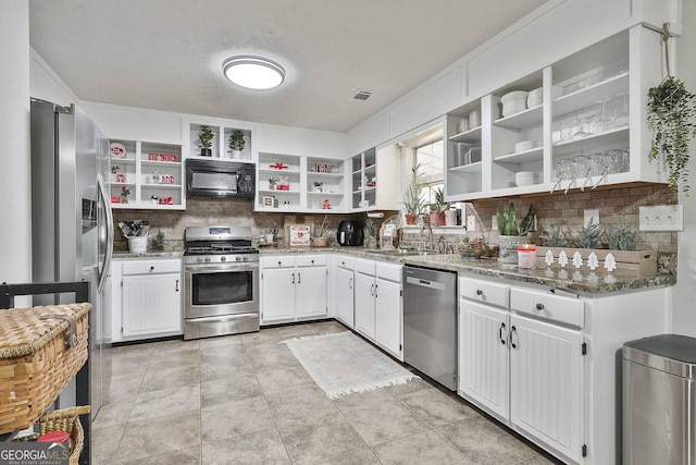 kitchen featuring stone counters, appliances with stainless steel finishes, backsplash, and white cabinetry