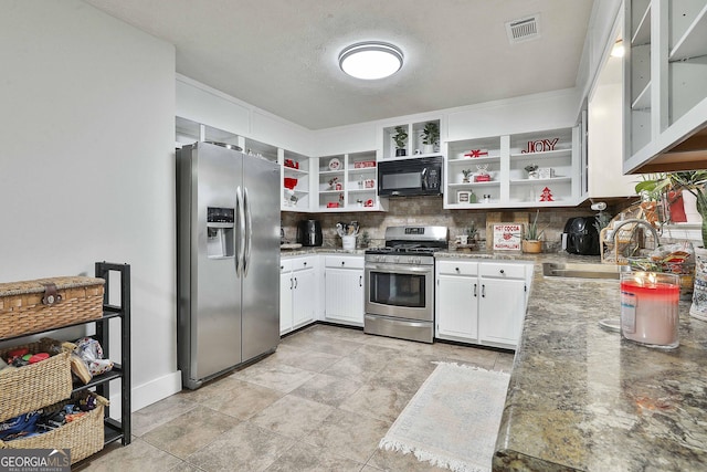 kitchen featuring appliances with stainless steel finishes, backsplash, light stone counters, sink, and white cabinetry