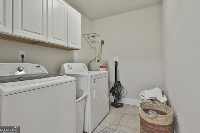 laundry room with cabinets, light tile patterned floors, a textured ceiling, and washing machine and dryer