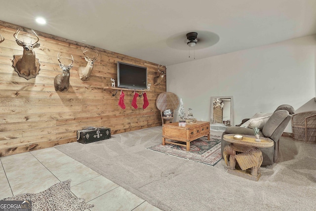 tiled living room featuring ceiling fan and wooden walls