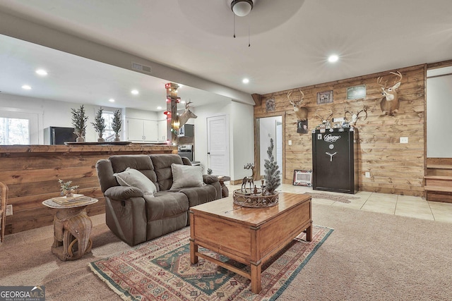 living room featuring light carpet, ceiling fan, and wooden walls