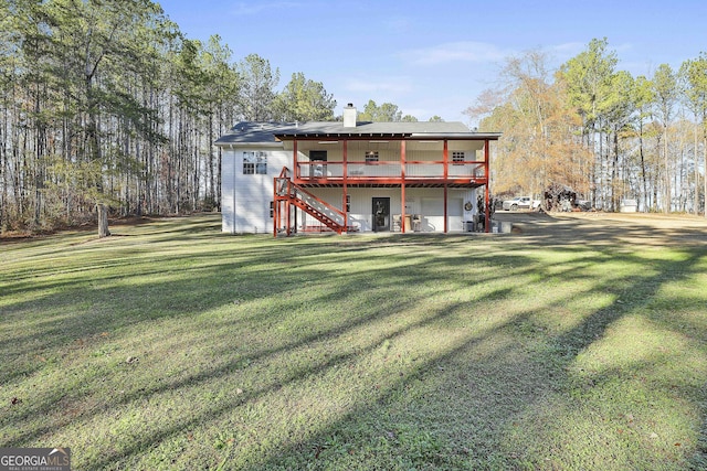 rear view of property featuring a lawn and a wooden deck