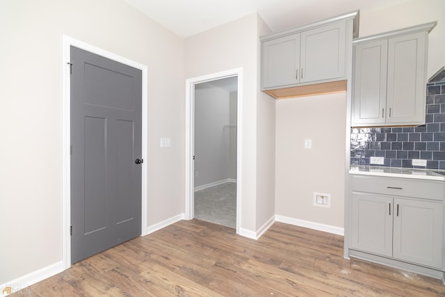 kitchen featuring gray cabinetry, backsplash, and light hardwood / wood-style flooring