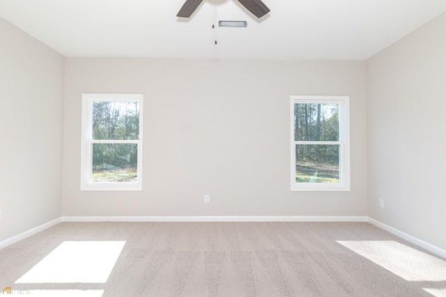 spare room featuring ceiling fan, light colored carpet, and a wealth of natural light