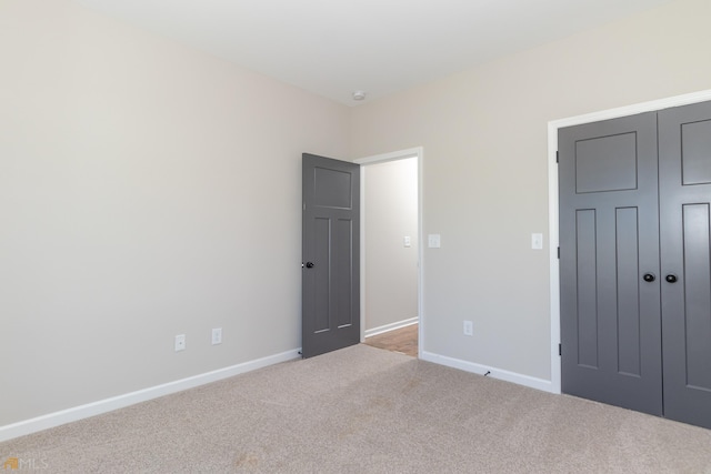 unfurnished bedroom with light carpet and a closet