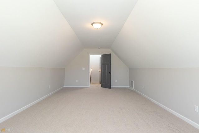 additional living space featuring light colored carpet and lofted ceiling