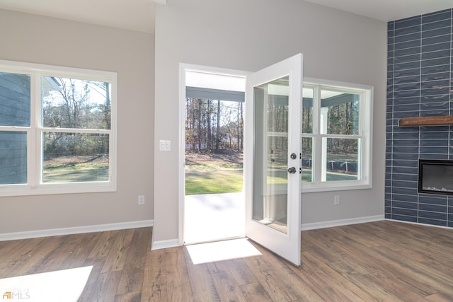 entryway with wood-type flooring, tile walls, and a tiled fireplace