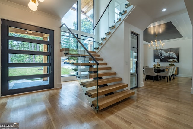 interior space featuring a wealth of natural light, hardwood / wood-style floors, crown molding, and an inviting chandelier