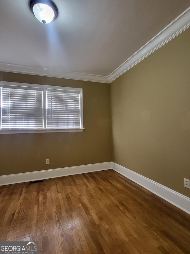 spare room featuring hardwood / wood-style flooring and crown molding