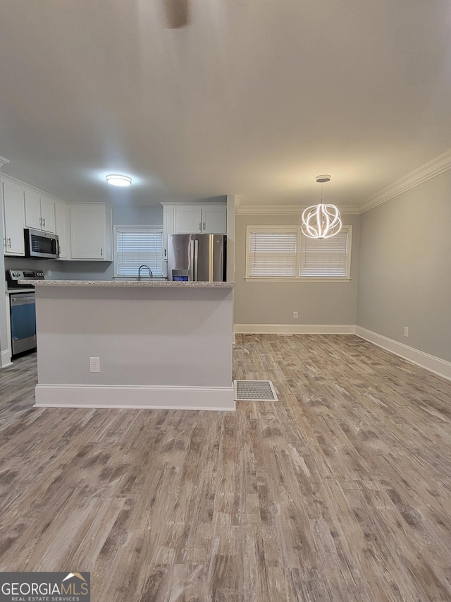 kitchen with white cabinetry, ornamental molding, appliances with stainless steel finishes, and light hardwood / wood-style flooring