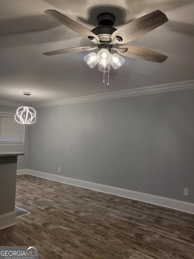 empty room featuring ceiling fan with notable chandelier, dark hardwood / wood-style flooring, and crown molding