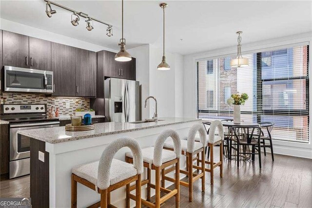966 Moda Dr, Atlanta, GA 30316 - kitchen featuring dark hardwood / wood-style floors, an island with sink, appliances with stainless steel finishes, dark brown cabinets, and a breakfast bar area