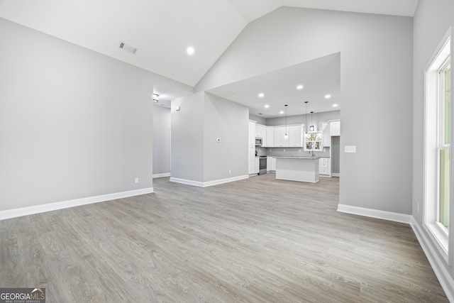 unfurnished living room with high vaulted ceiling and light hardwood / wood-style floors