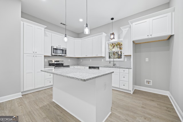 kitchen with light stone counters, appliances with stainless steel finishes, a center island, and white cabinets