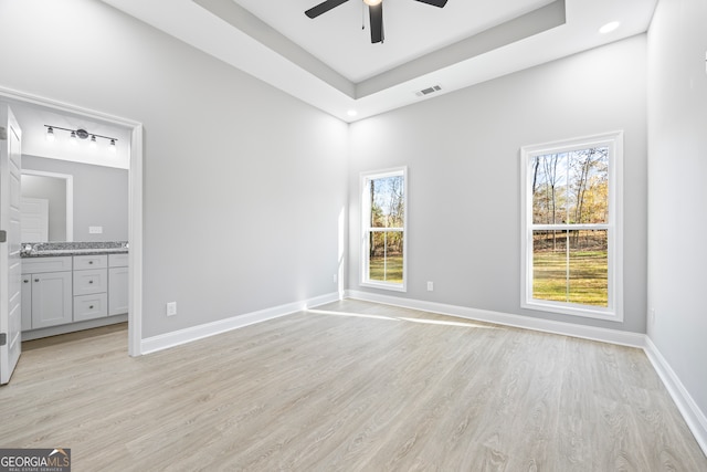 unfurnished bedroom with ceiling fan, ensuite bath, light hardwood / wood-style floors, and multiple windows