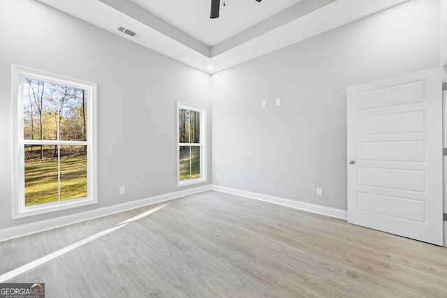 empty room featuring a wealth of natural light, light hardwood / wood-style floors, and ceiling fan